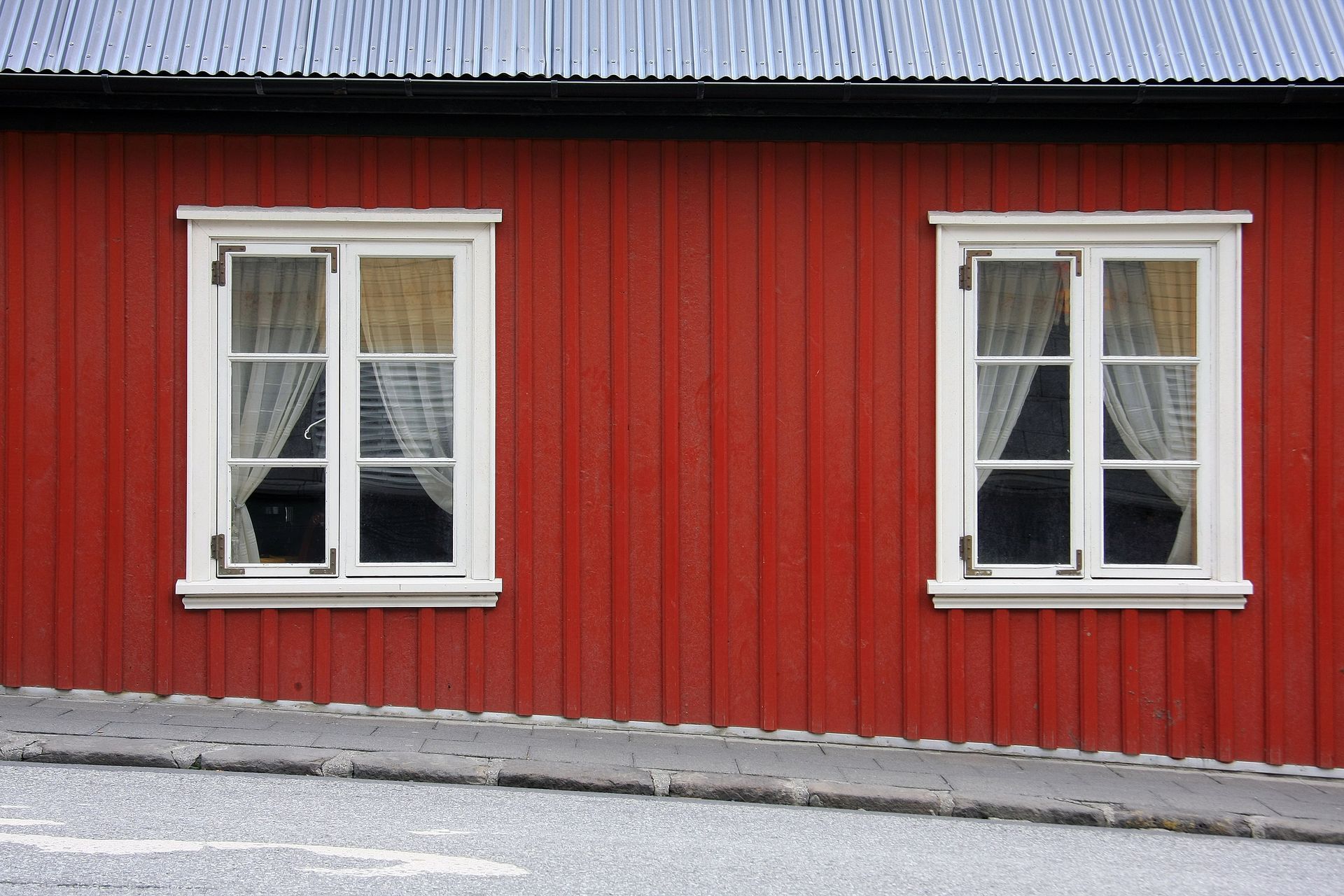 A red building with white windows and curtains