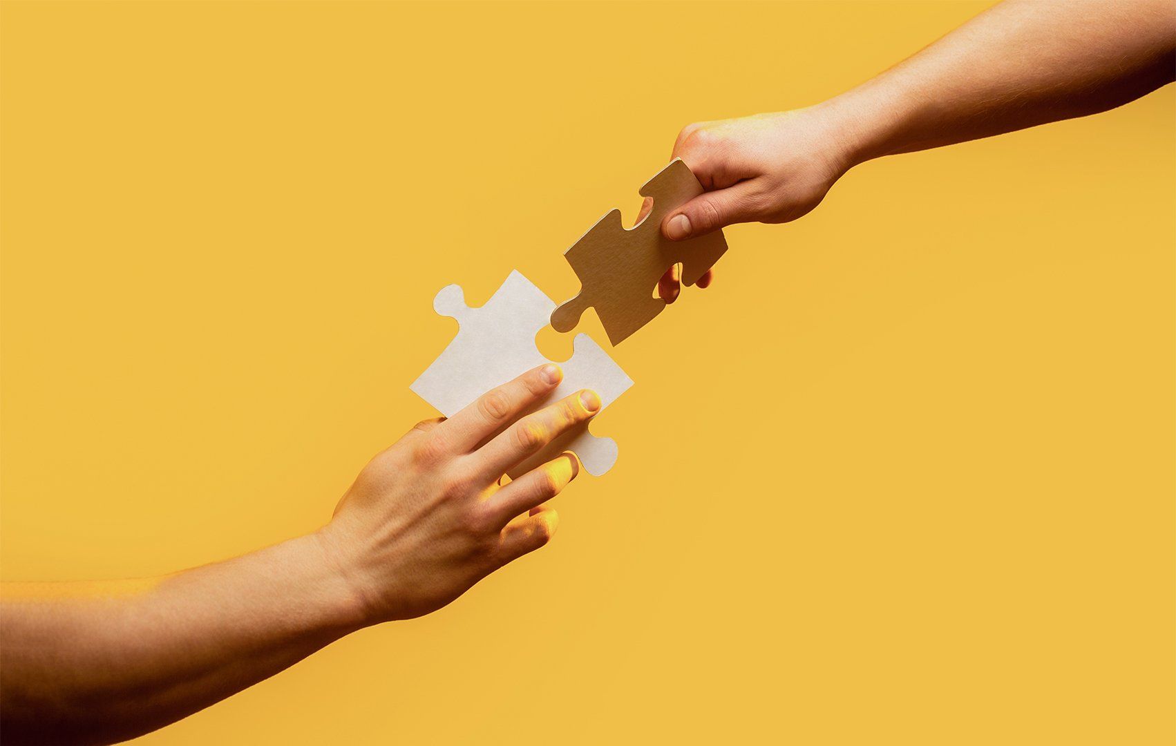 Closeup hands of man connecting jigsaw puzzle.