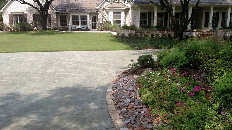 Suburban home with a stone driveway, green lawn, and flower bed lining the front yard.