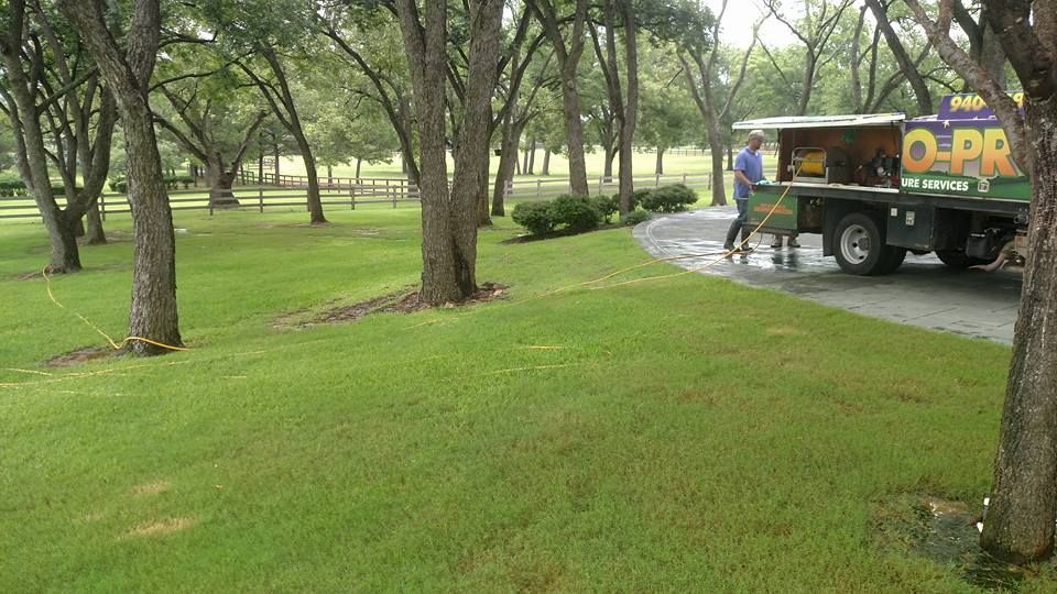 Lawn care truck on a paved path in a green park with trees and mowed grass.