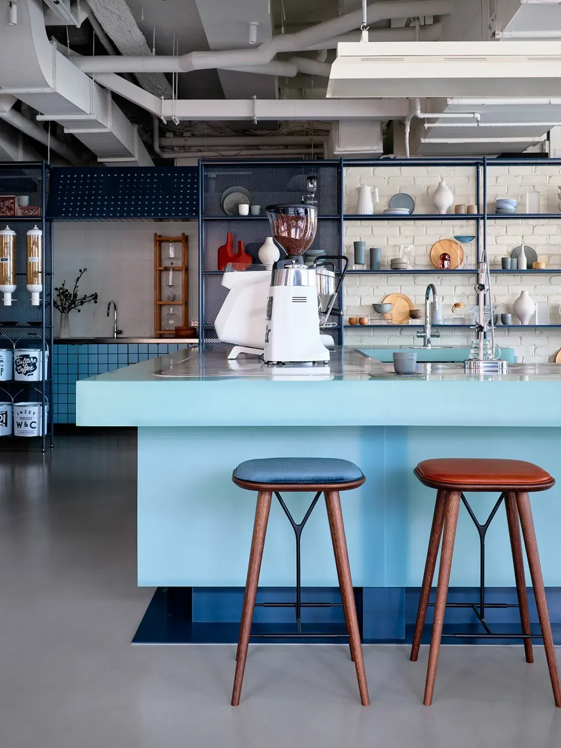 A kitchen with a blue island and three stools.