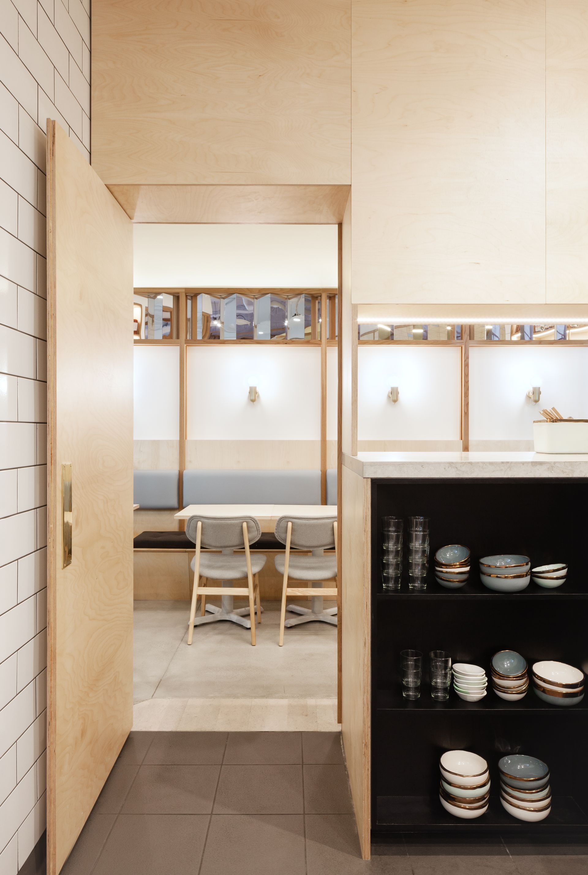A room with a table and chairs and a shelf with bowls on it