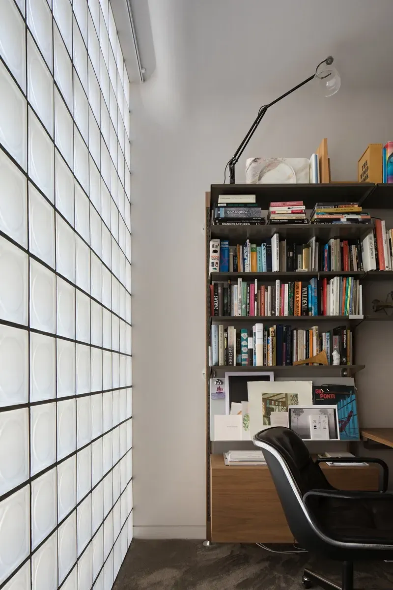 A corner of a room with a bookshelf and a chair