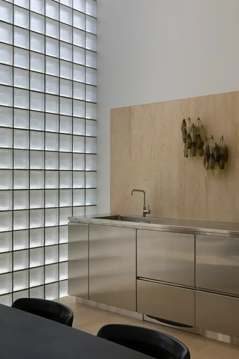 A kitchen with stainless steel cabinets and a glass block wall