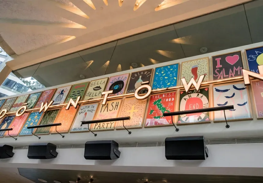 A row of posters hanging on a wall above a sign that says downtown.