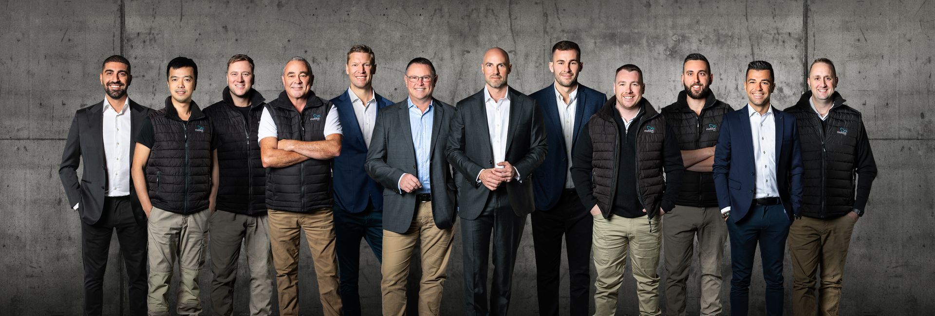 A group of men are standing next to each other in front of a concrete wall.