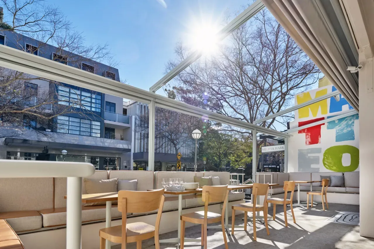 A restaurant with tables and chairs outside on a sunny day.