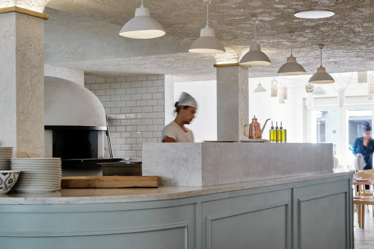 A man is standing behind a counter in a restaurant.