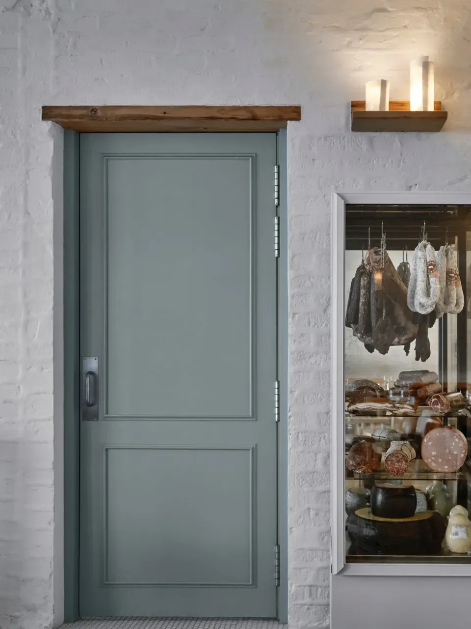 A blue door is sitting in front of a window with meat hanging on it.