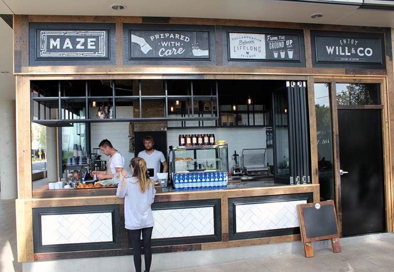 A woman is standing at a counter in front of a restaurant called maze.