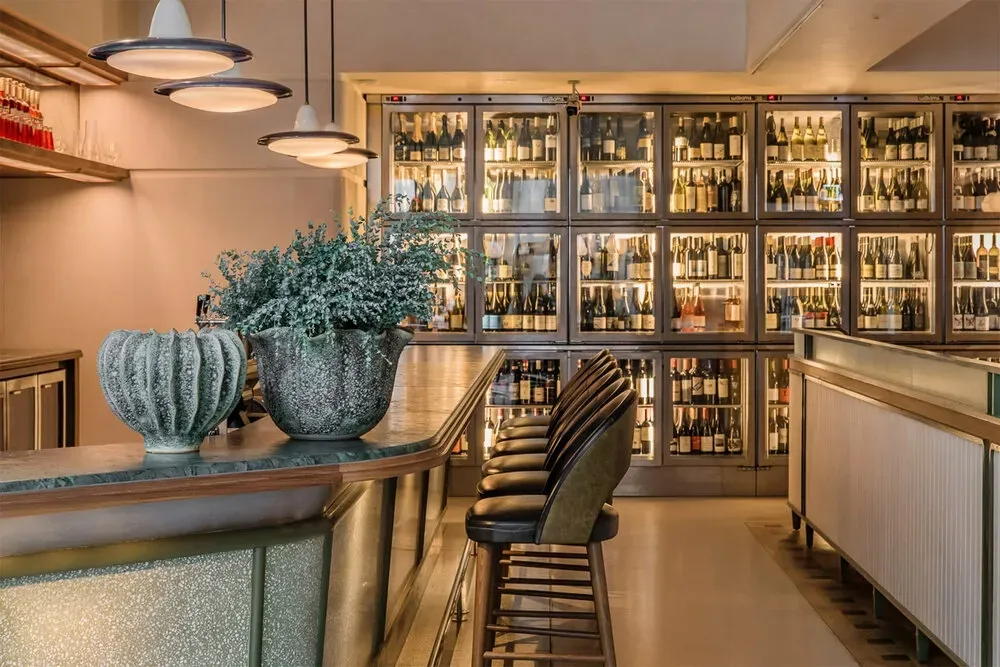 A bar in a restaurant with a lot of bottles on the wall.