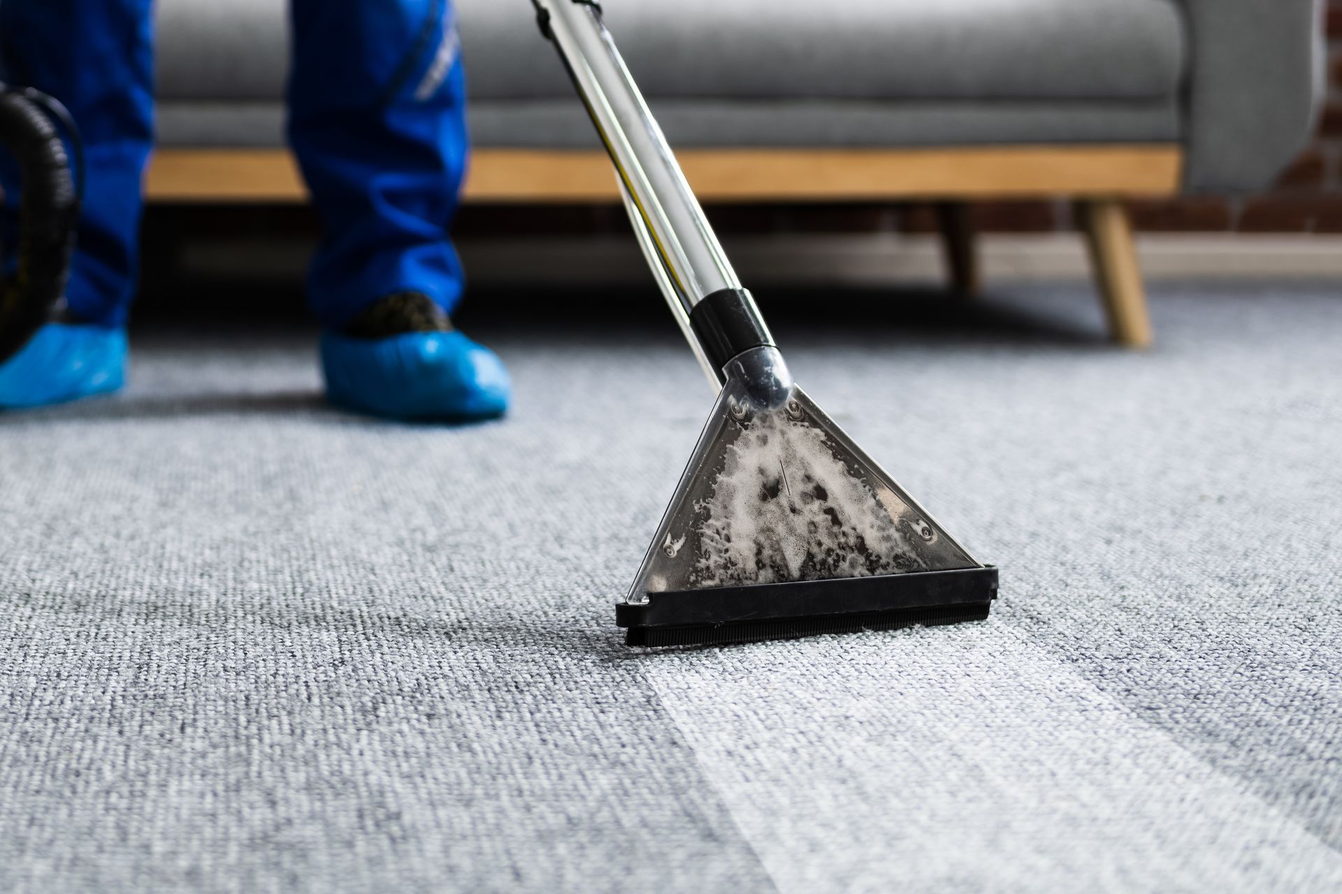 A person is cleaning a carpet with a vacuum cleaner.