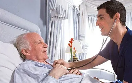 A nurse is listening to an elderly man 's heartbeat with a stethoscope.