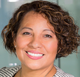 A woman with curly hair is smiling for the camera.