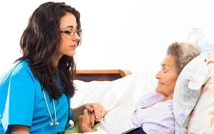 A nurse is talking to an elderly woman in a hospital bed.