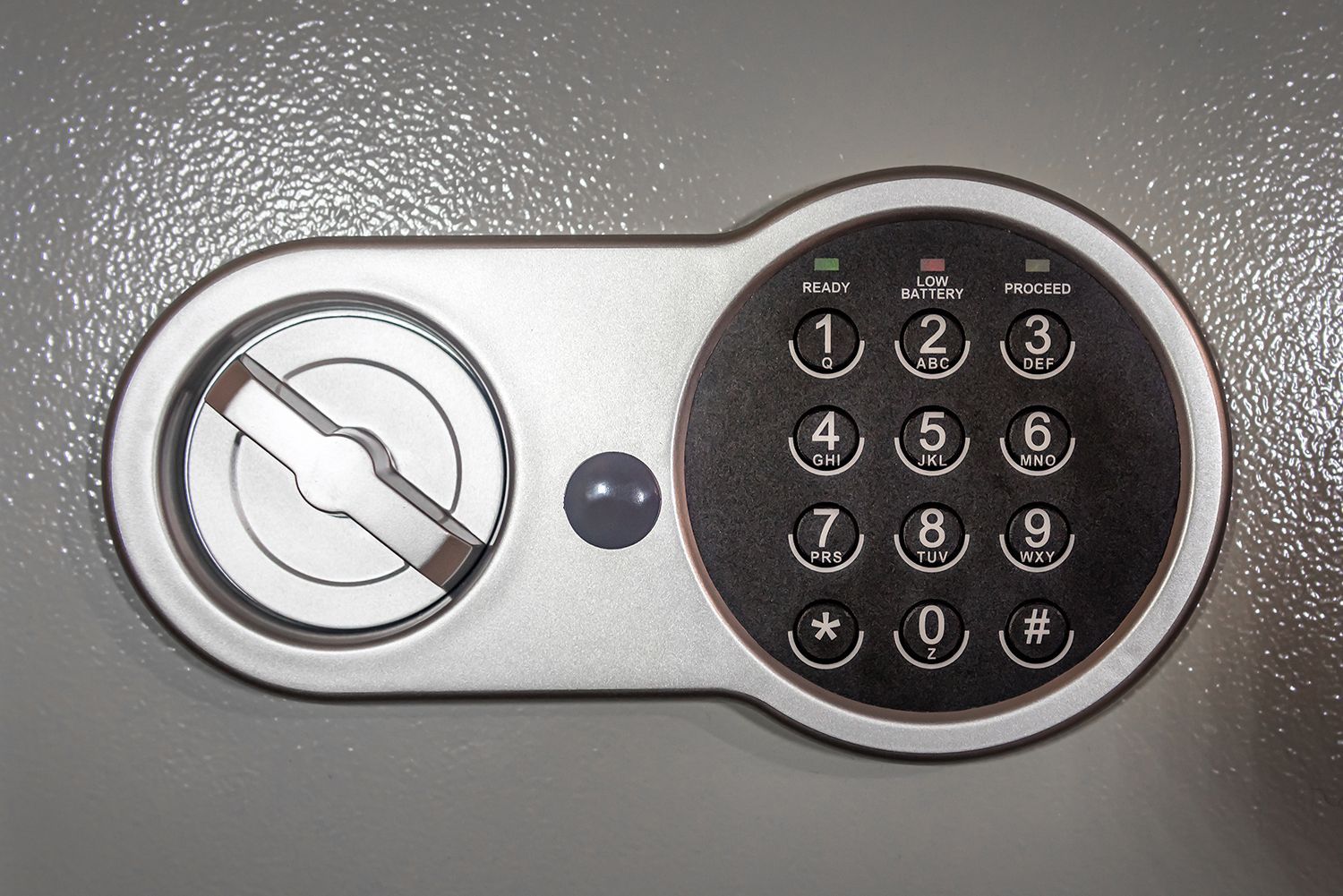 Close-up of a silver digital safe with a round keypad and keyhole on a gray surface Close-up of a silver digital safe with a round keypad and keyhole on a gray surface