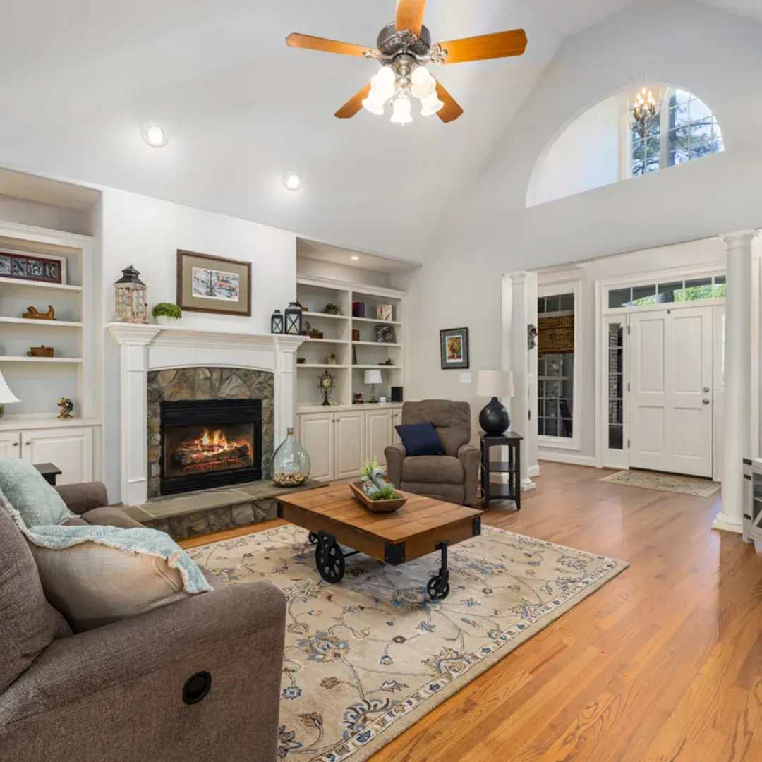 A living room with a fireplace and a ceiling fan