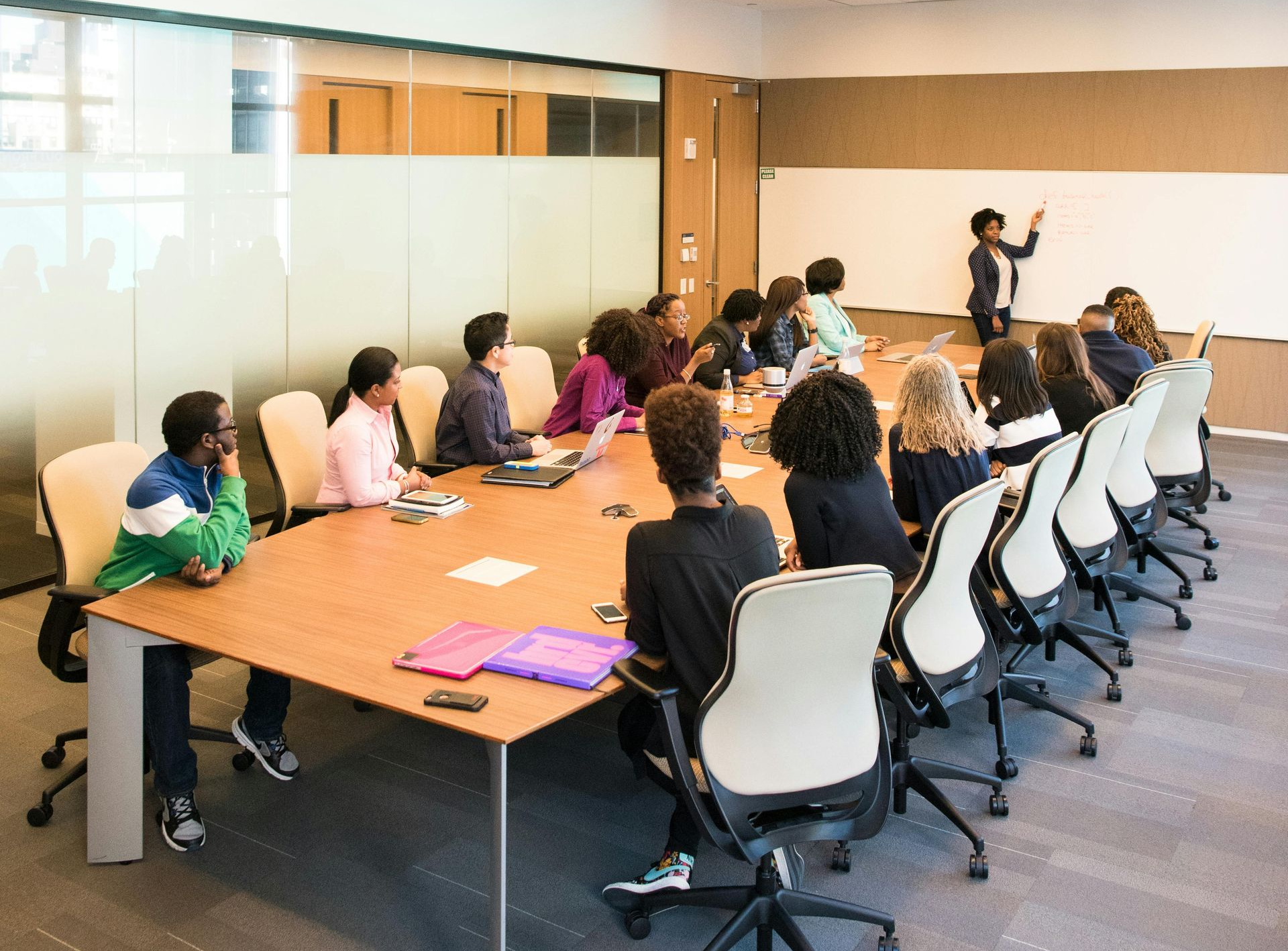 An image showing a color team review. A review lead is at the front of the room leading the debrief of a red team evaluation.