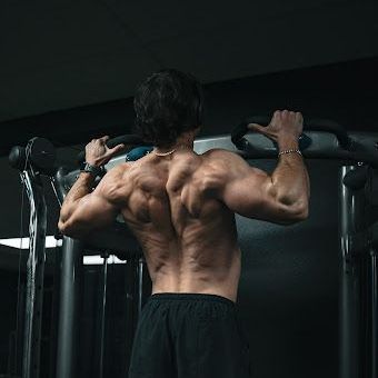 A man is doing pull ups on a bar in a gym.