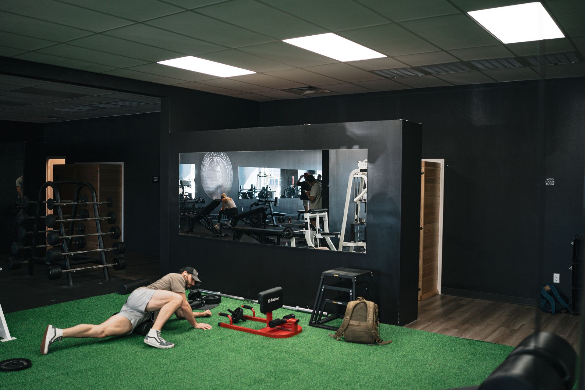 A man is doing push ups on the grass in a gym.