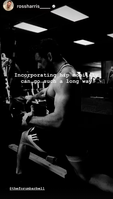 A man is sitting on a bench in a gym holding a dumbbell.