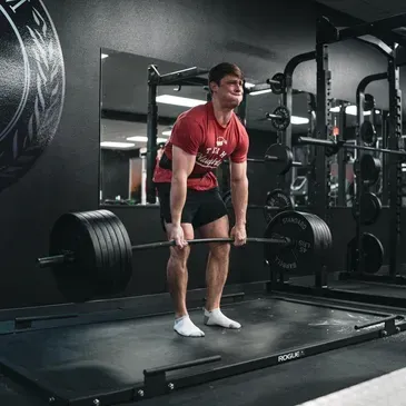 A man is lifting a barbell in a gym.