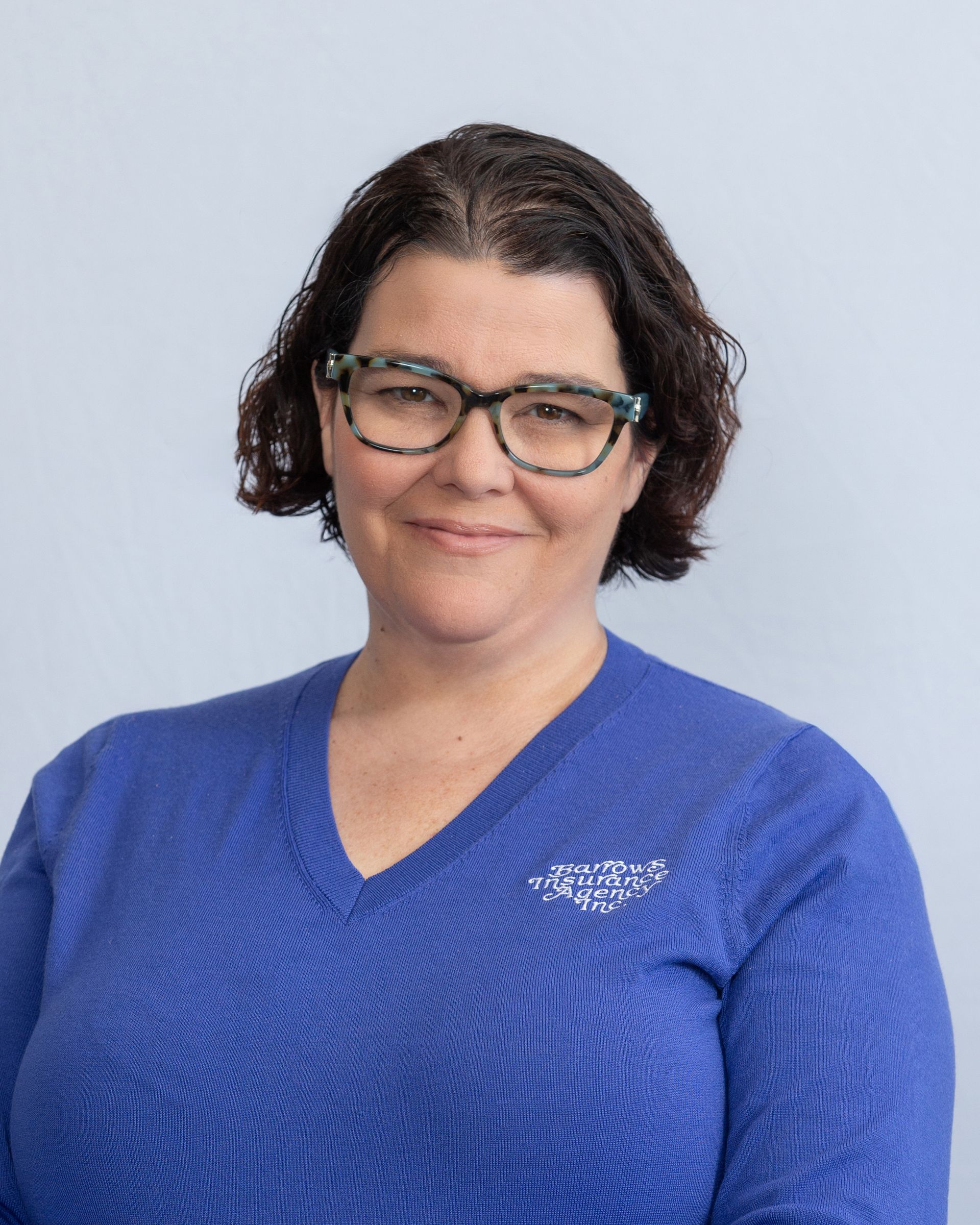 Person in glasses and blue sweater smiling against a light background