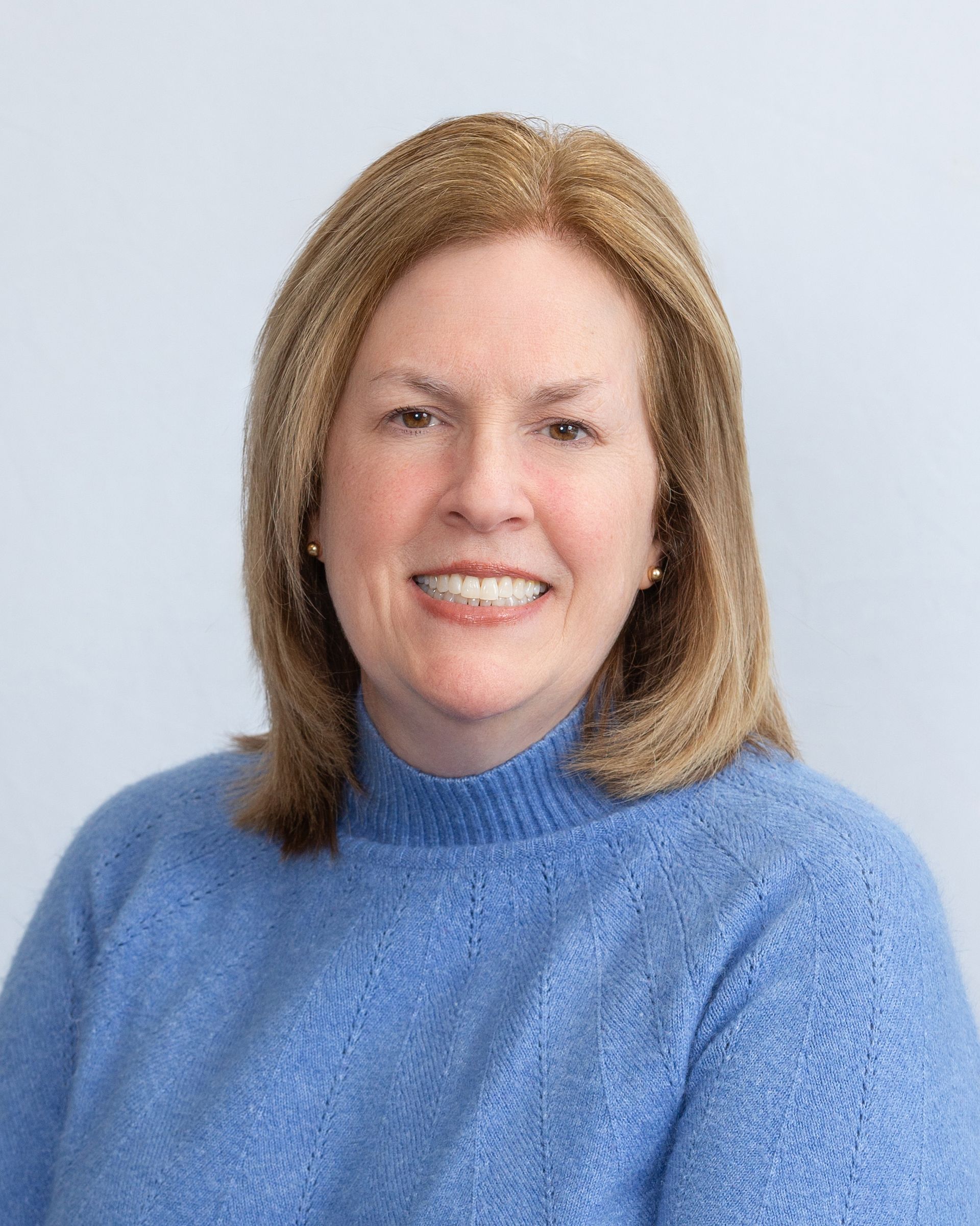 Portrait of a smiling person in a blue sweater against a light background