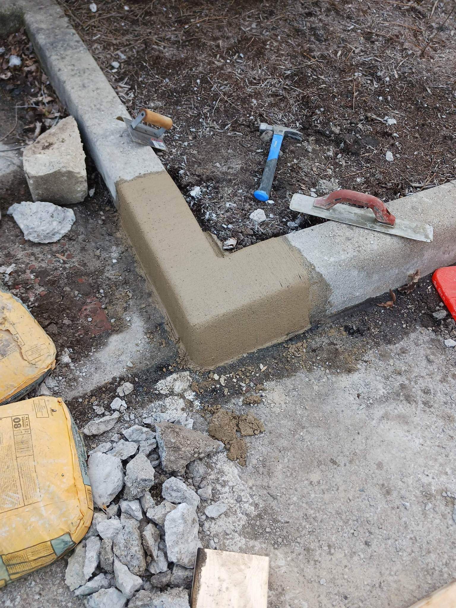 A person is laying concrete on a sidewalk with a trowel.