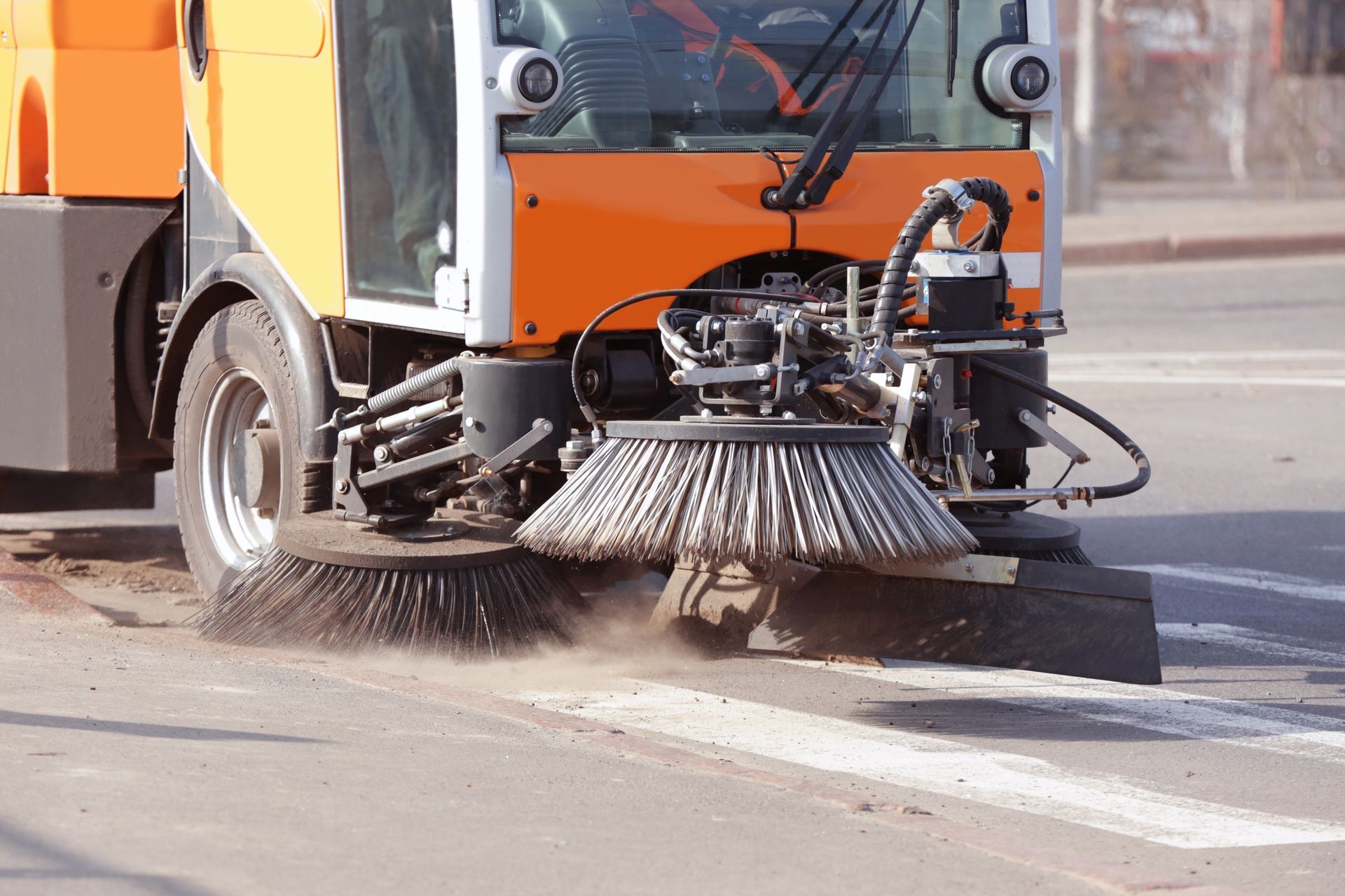 Construction sweeping service vehicle cleaning roadway and removing dust from work site.