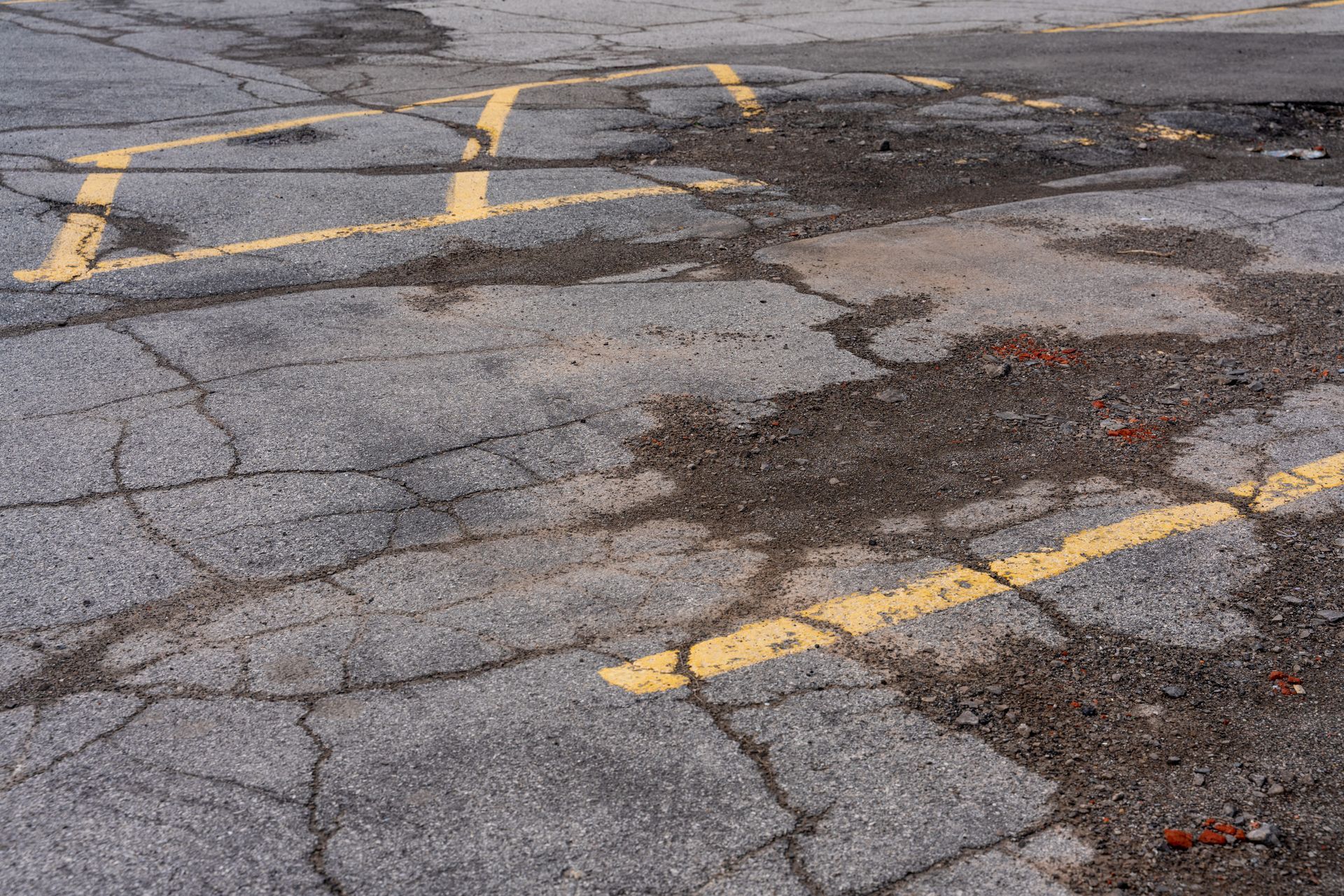 Parking lot on asphalt with yellow marked parking lines and old cracked pavement.