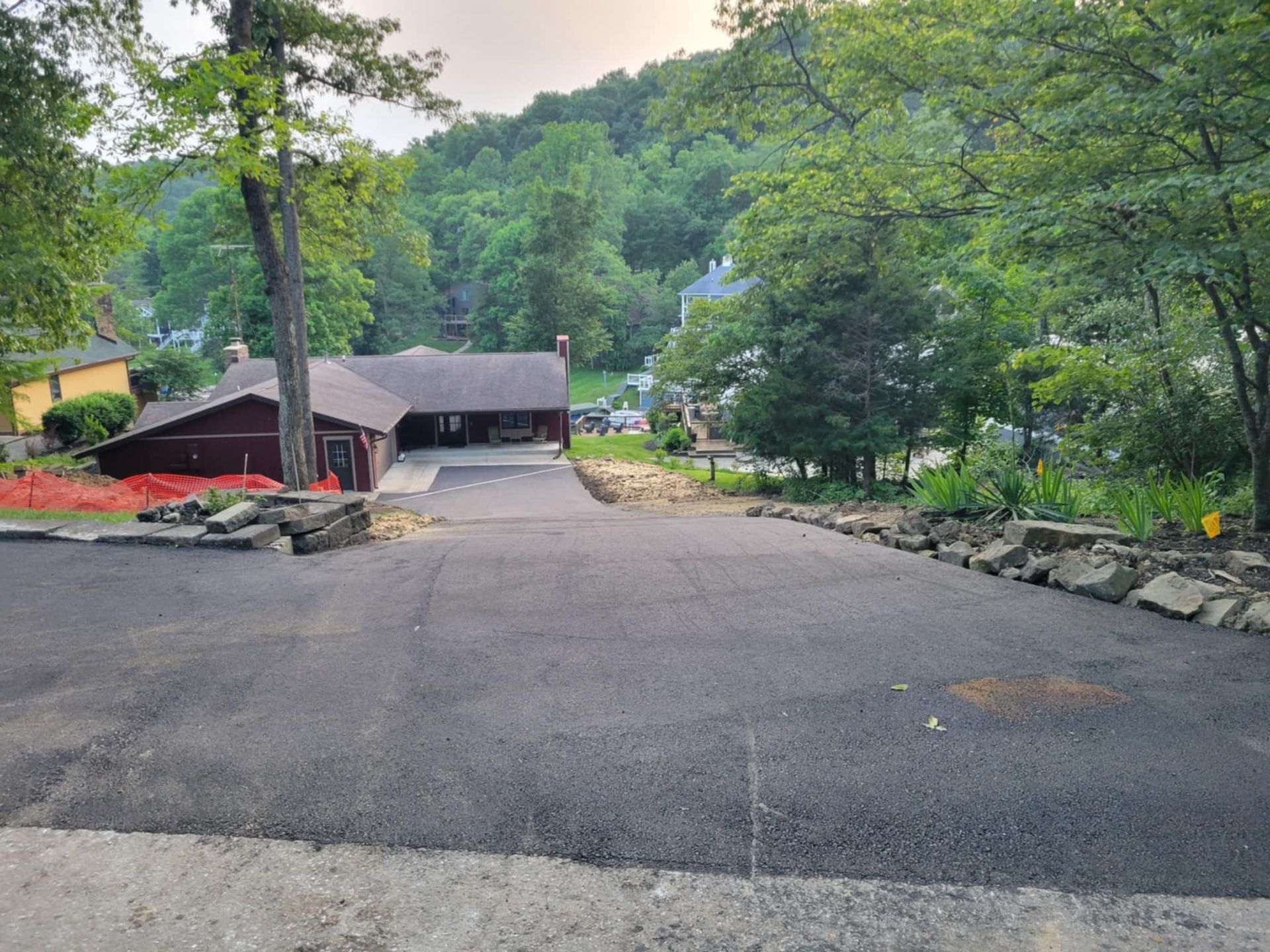 A large driveway leading to a house in the woods.