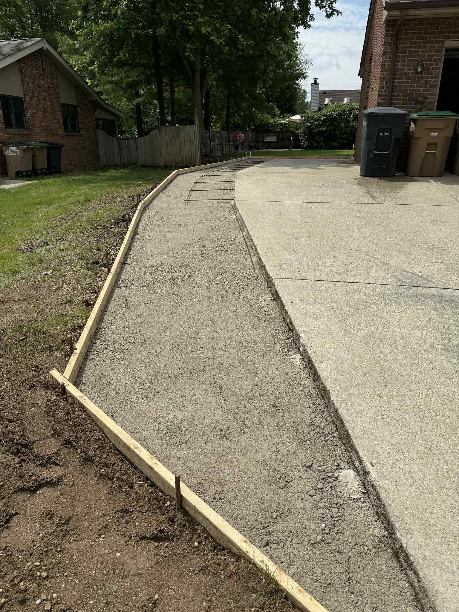 A concrete walkway is being built in front of a house.