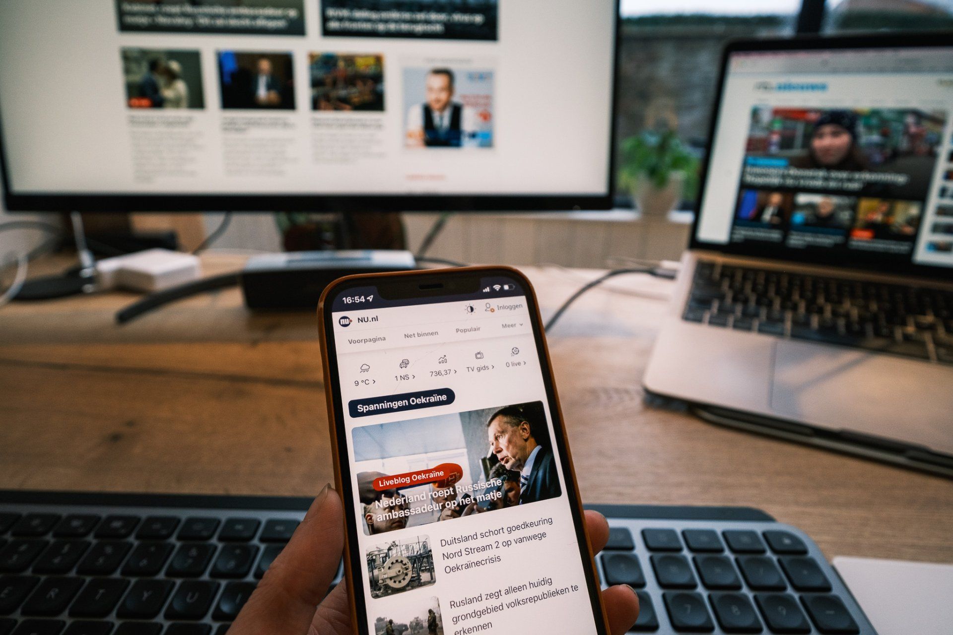 Afbeelding van een telefoon en twee beeldschermen met nieuwsmedia