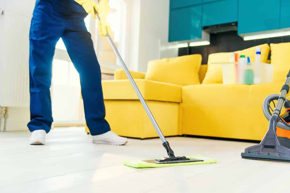 A Person Is Mopping The Floor In A Living Room — FNQ Cleaning Services in Mooroobool, QLD