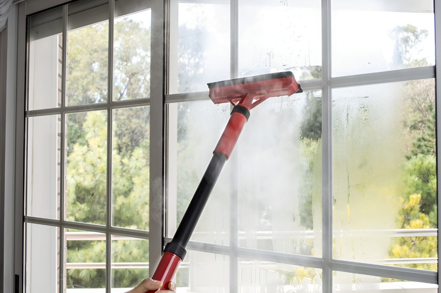 A Person is Cleaning a Window With a Steam Cleaner — FNQ Cleaning Services in Mooroobool, QLD