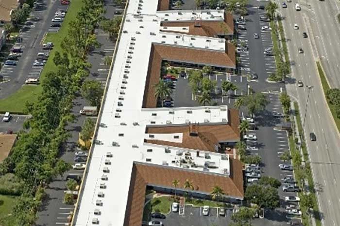 An aerial view of a group of buildings with white roofs surrounded by trees.