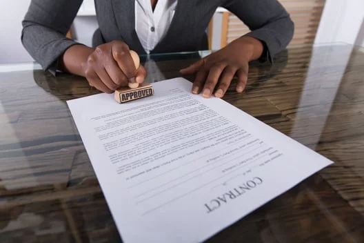 Person stamping a contract document on a glass desk