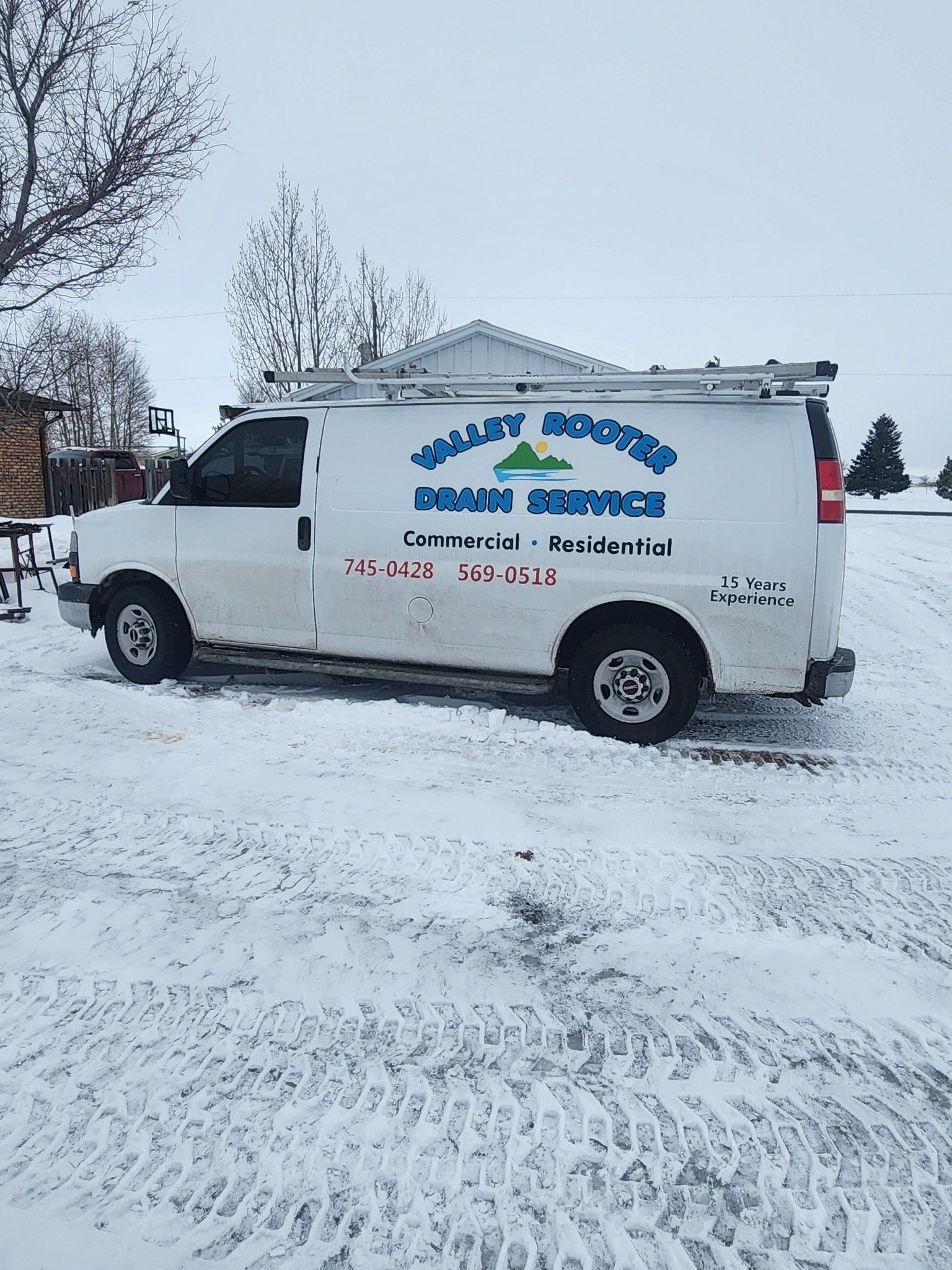 A white work van parked in snow, labeled 