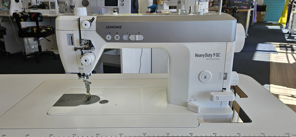 White portable sewing machine with purple controls and carrying handle on a white background