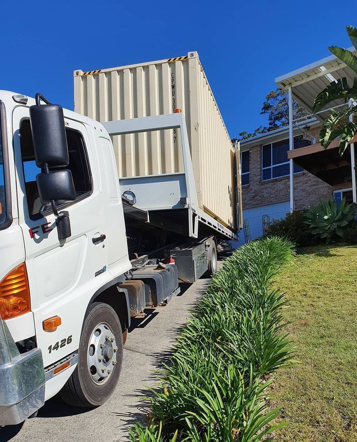 A White Truck With A Container On The Back Is Parked In Front Of A House — Taree Containers in Taree, NSW