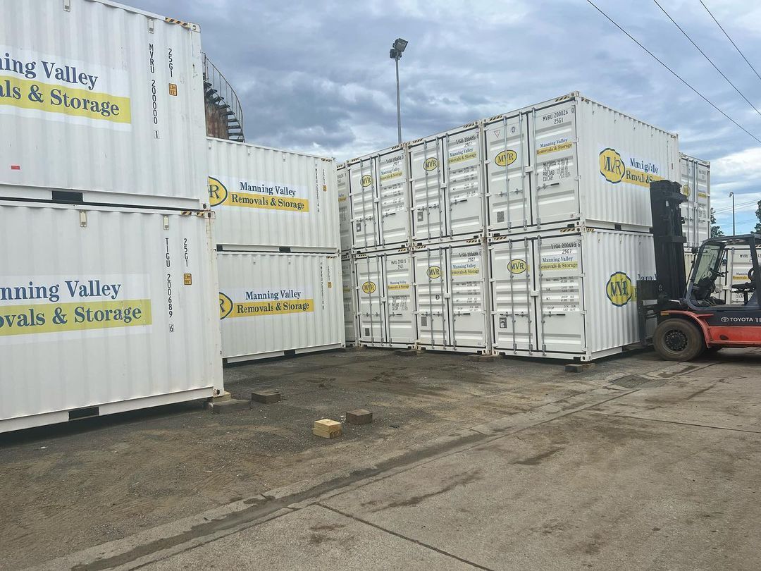 A Forklift Is Moving A Bunch Of Shipping Containers In A Parking Lot — Taree Containers in Taree, NSW