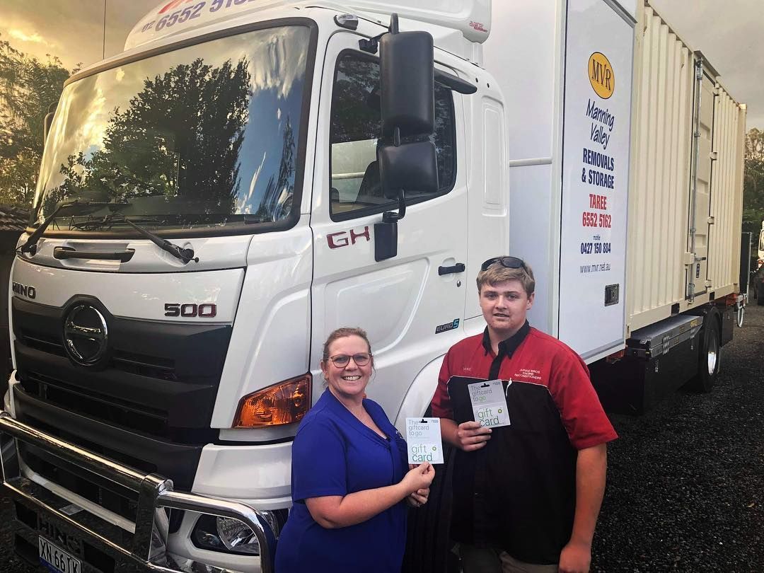 A Man And A Woman Are Standing In Front Of A Truck — Taree Containers in Taree, NSW