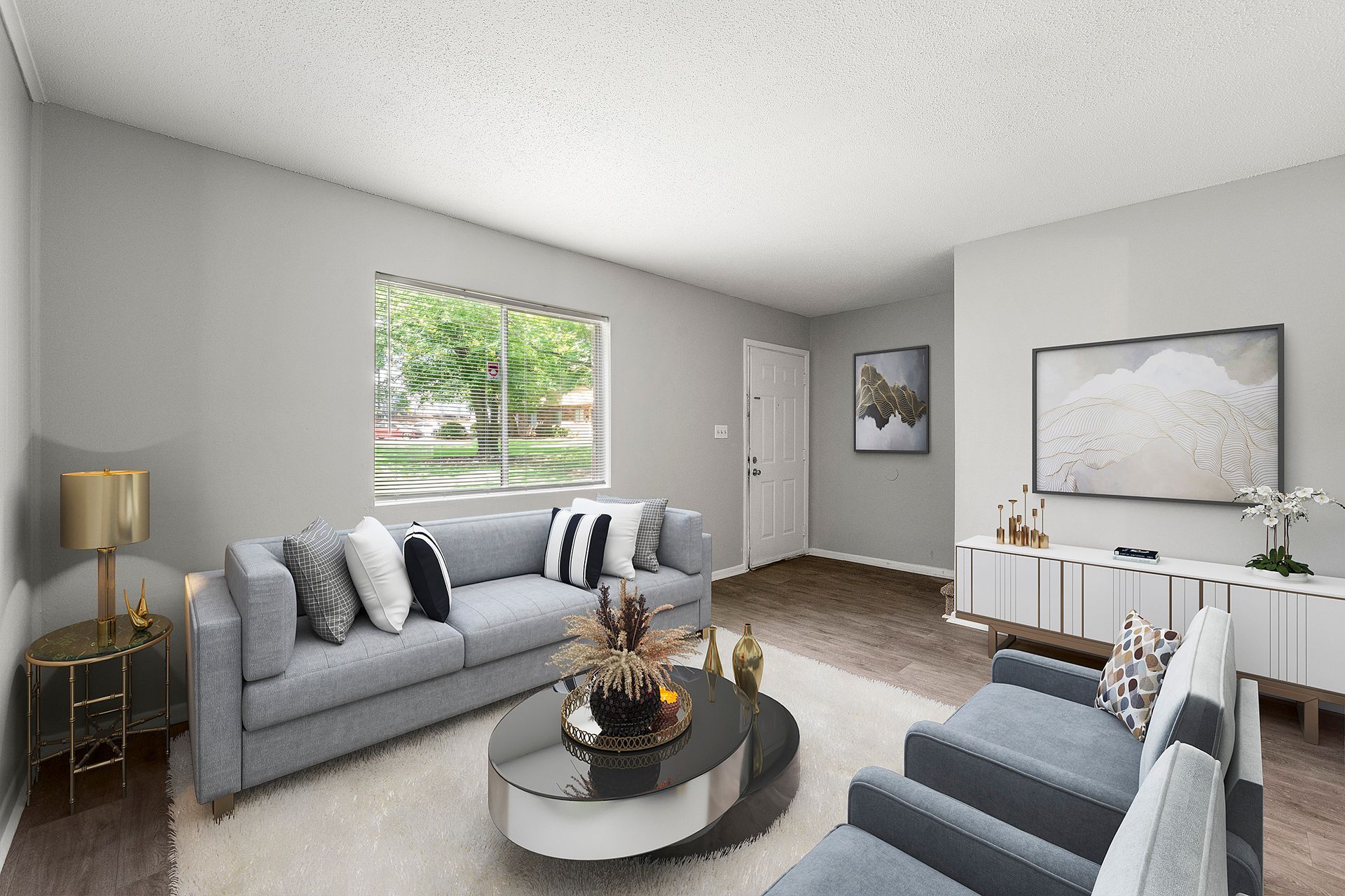 Bright modern living room with gray sofas, round coffee table, wall art, and large window with blinds