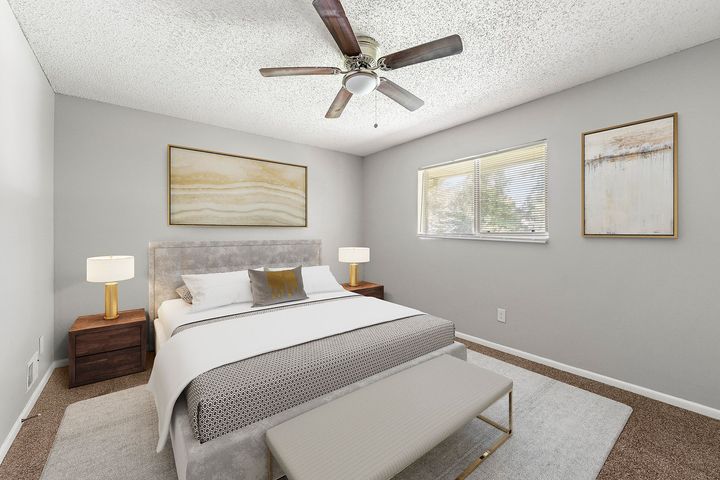 Bright bedroom with gray walls, white bed, bedside lamps, and ceiling fan.