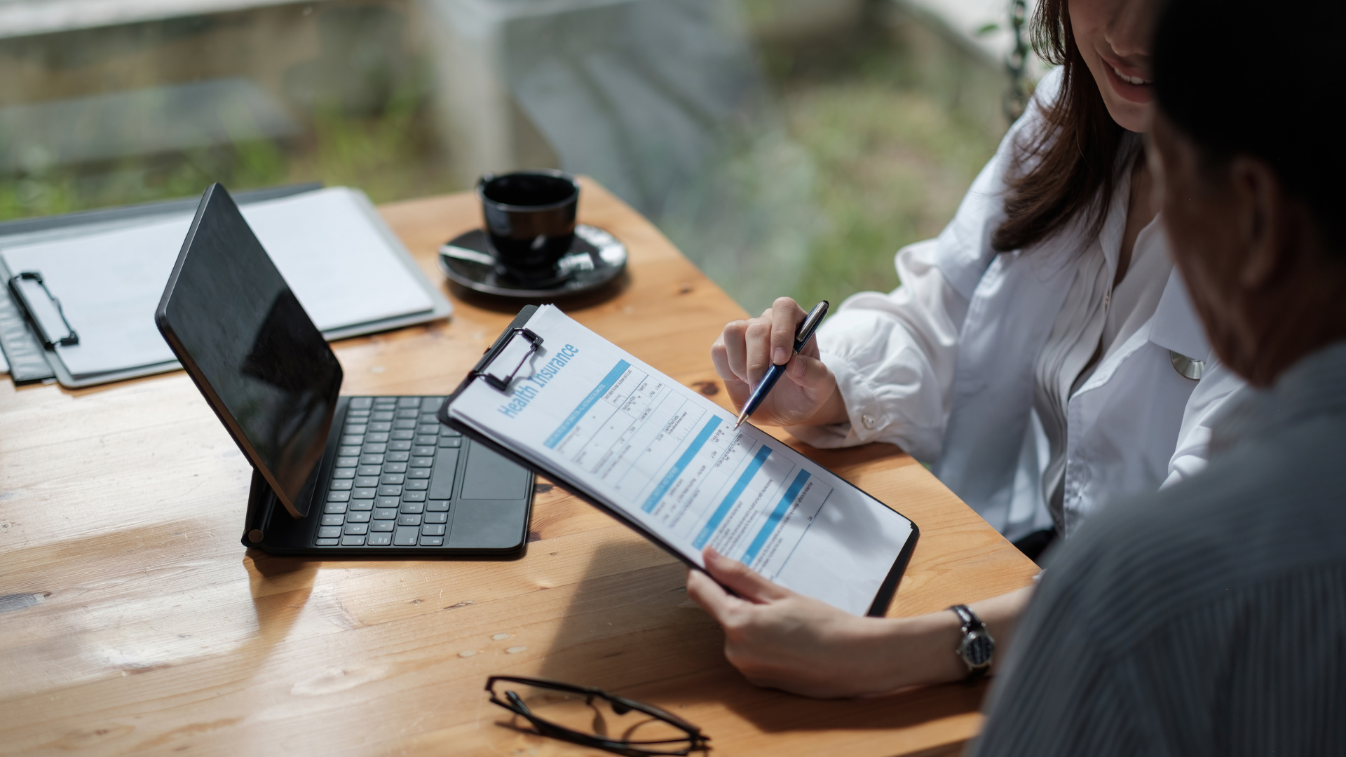 a man and a woman are sitting at a table looking at a clipboard .