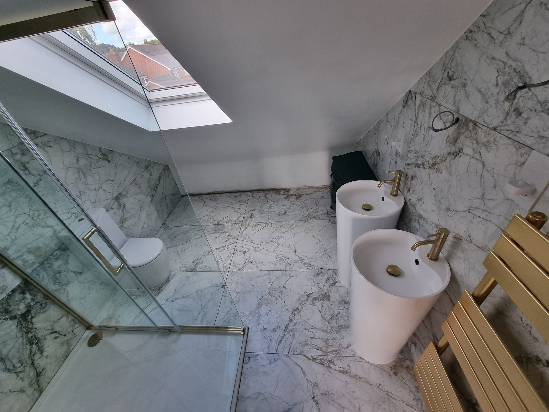 A bathroom with two sinks , a toilet and a skylight