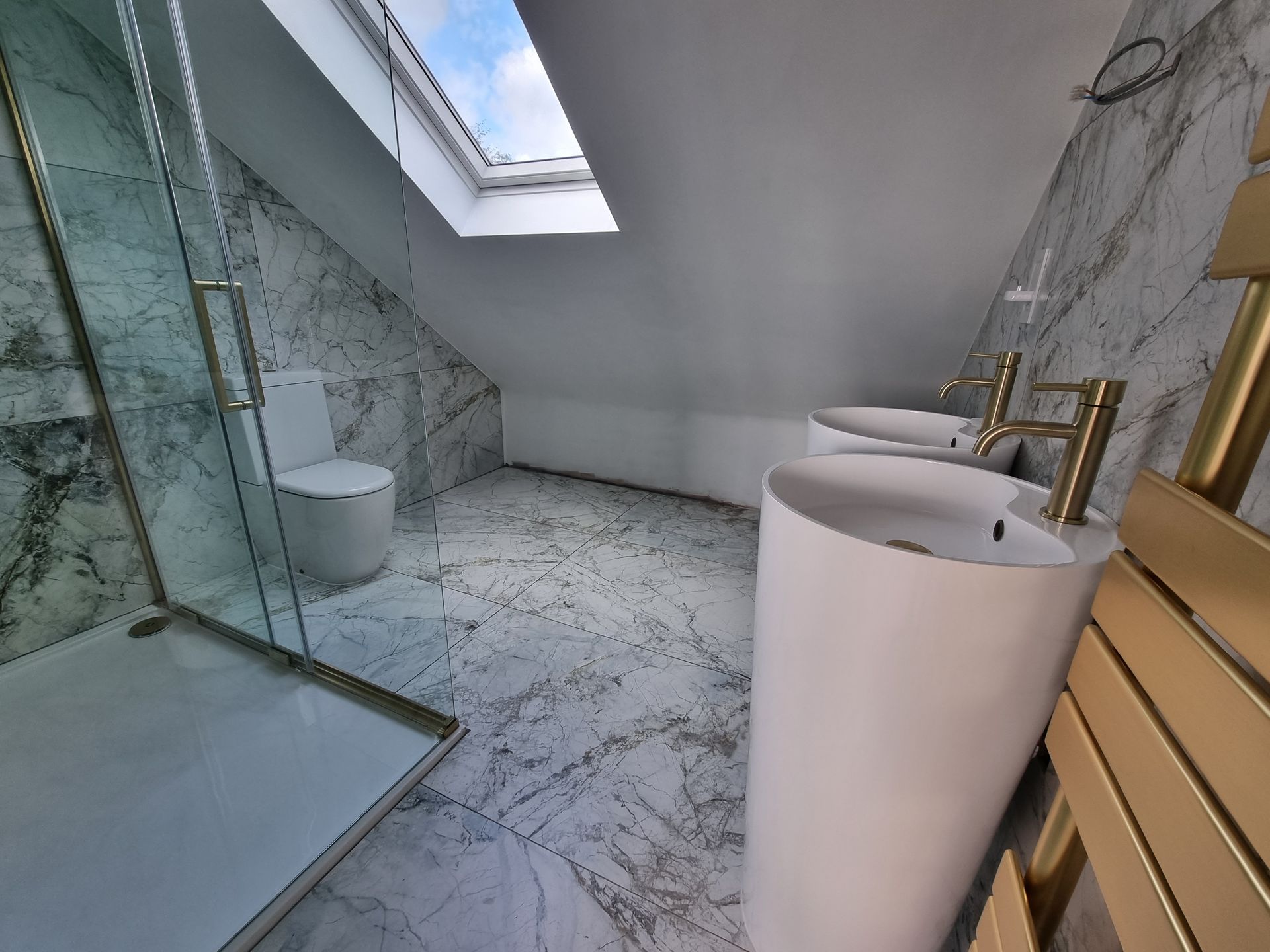 A bathroom with two sinks , a toilet and a skylight.