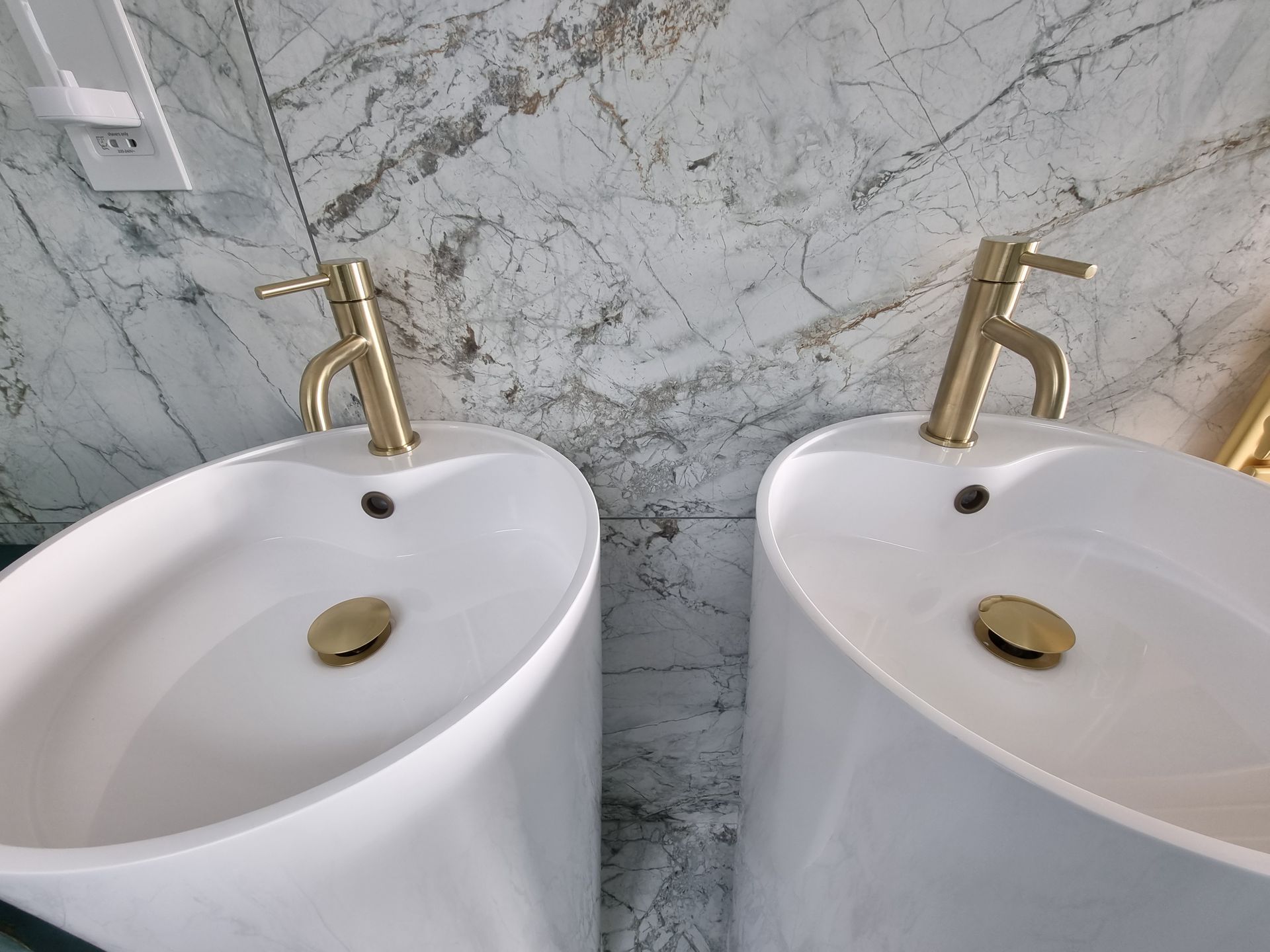 Two white sinks with gold faucets in a bathroom