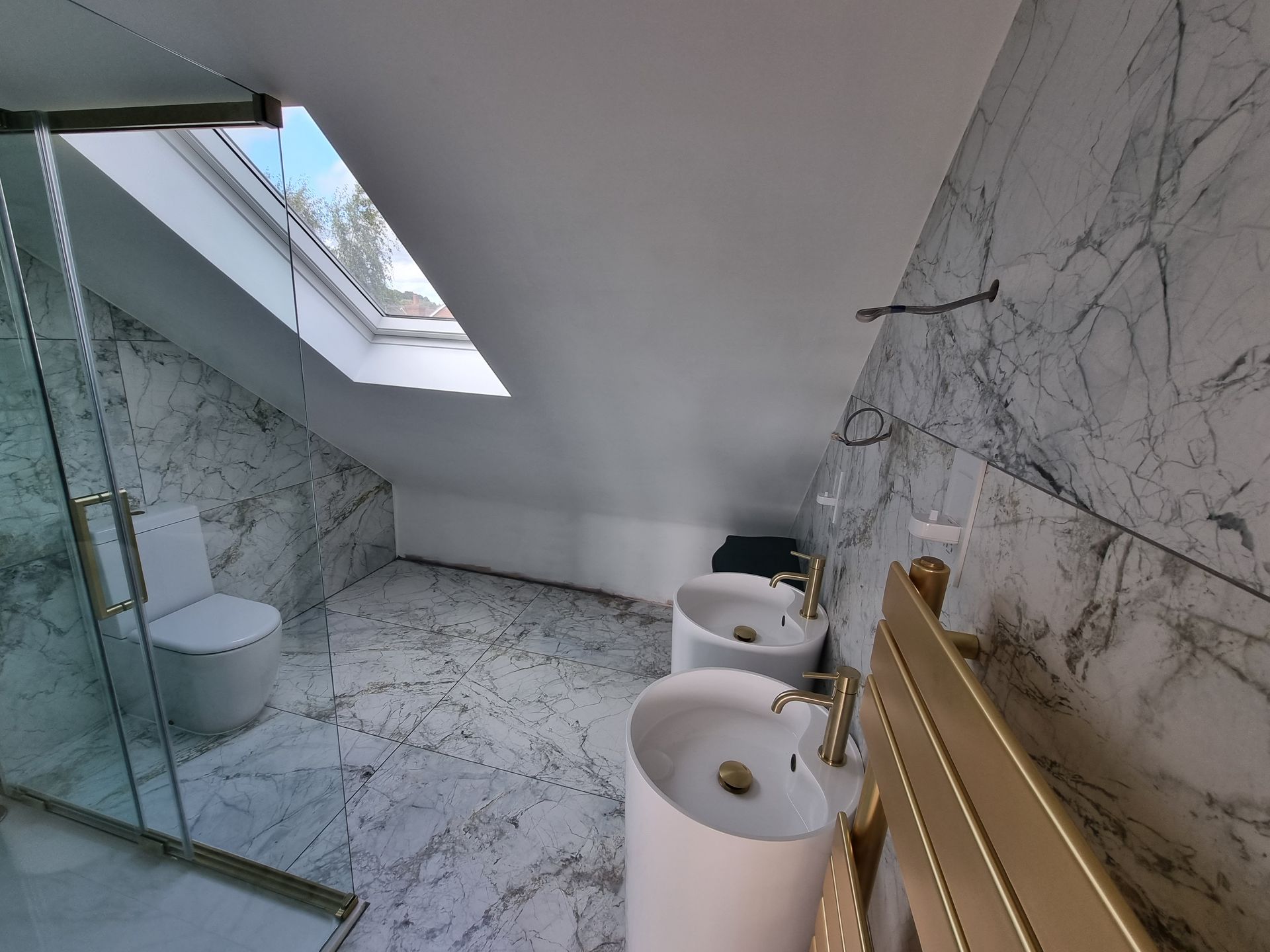 A bathroom with two sinks , a toilet and a skylight